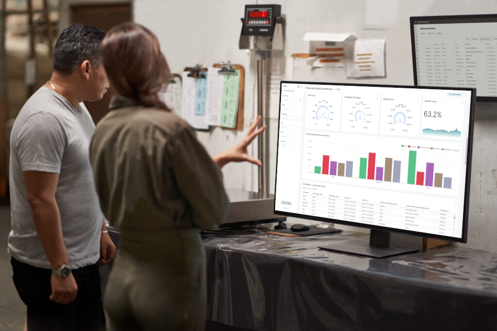 TV screen showing OEE Explorer dashboard with two people discussing